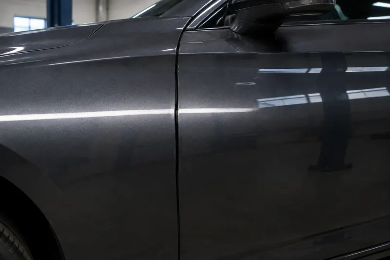 Close view of the gap between a front fender and a door on an otherwise clean grey car